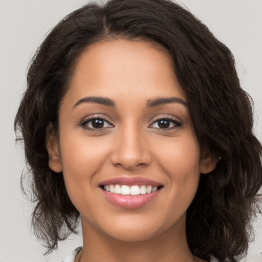 Joyful latino young-adult female with medium  brown hair and brown eyes