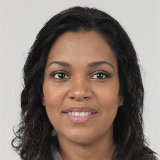 Joyful black young-adult female with long  brown hair and brown eyes