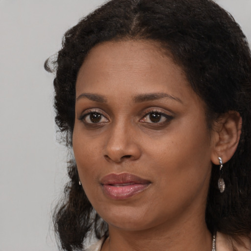 Joyful black young-adult female with long  brown hair and brown eyes