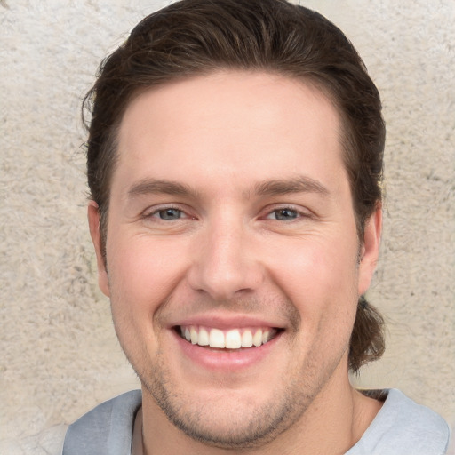 Joyful white young-adult male with short  brown hair and grey eyes