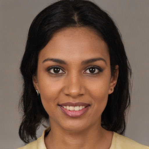 Joyful black young-adult female with long  brown hair and brown eyes
