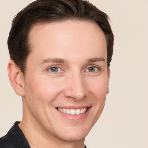 Joyful white young-adult male with short  brown hair and grey eyes