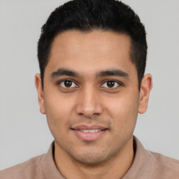 Joyful latino young-adult male with short  black hair and brown eyes