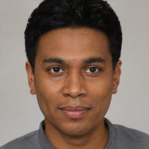 Joyful black young-adult male with short  black hair and brown eyes