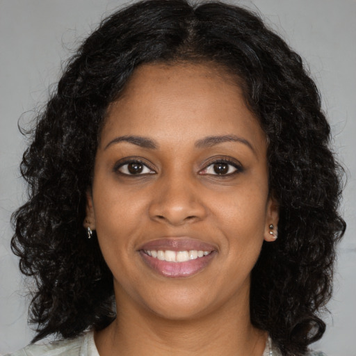 Joyful black young-adult female with long  brown hair and brown eyes
