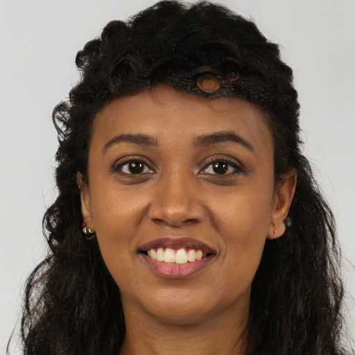 Joyful black young-adult female with long  brown hair and brown eyes