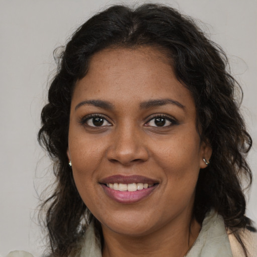 Joyful black adult female with long  brown hair and brown eyes