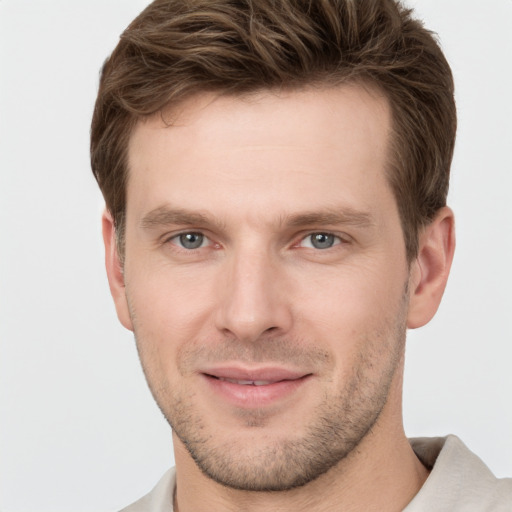 Joyful white young-adult male with short  brown hair and grey eyes