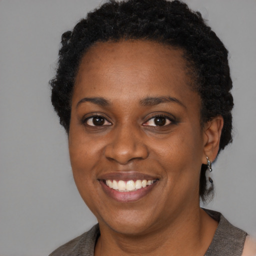 Joyful black young-adult female with short  black hair and brown eyes