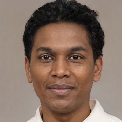 Joyful black young-adult male with short  black hair and brown eyes