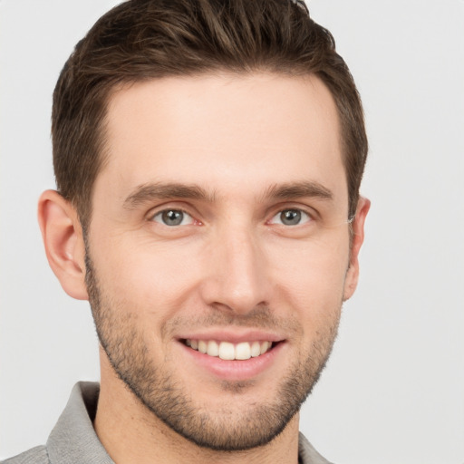 Joyful white young-adult male with short  brown hair and grey eyes