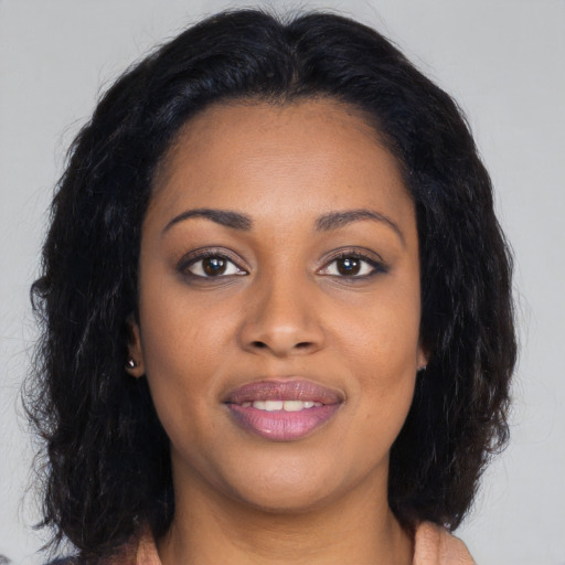 Joyful black young-adult female with long  brown hair and brown eyes