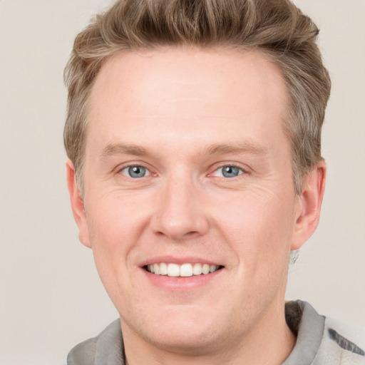 Joyful white adult male with short  brown hair and blue eyes