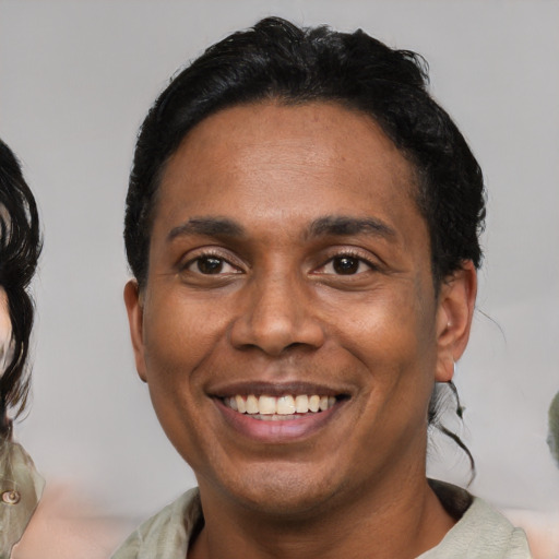 Joyful black young-adult male with medium  black hair and brown eyes