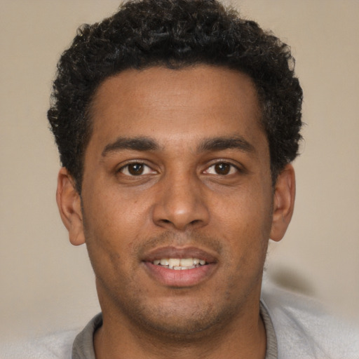 Joyful black young-adult male with short  brown hair and brown eyes