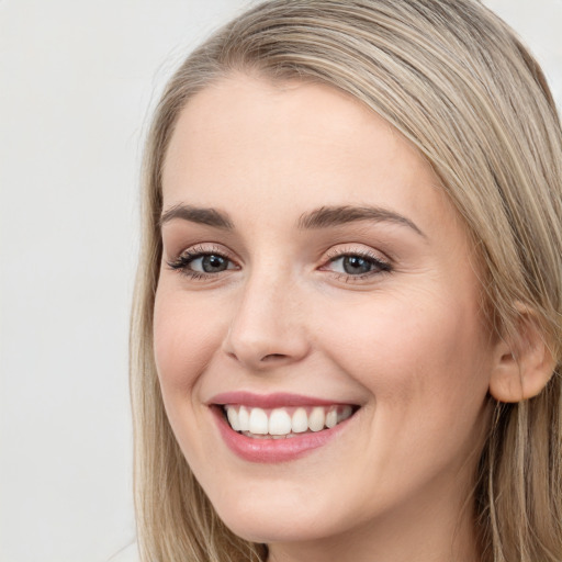 Joyful white young-adult female with long  brown hair and blue eyes