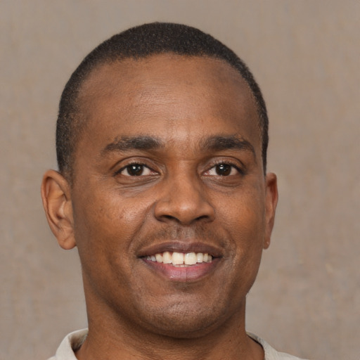 Joyful black young-adult male with short  brown hair and brown eyes