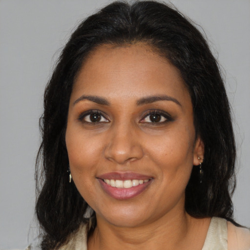 Joyful black young-adult female with long  brown hair and brown eyes
