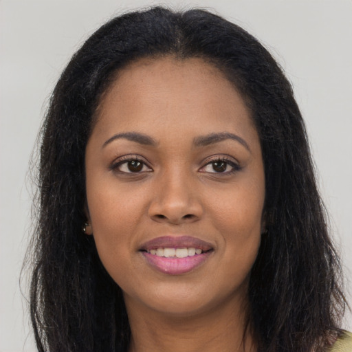 Joyful black young-adult female with long  brown hair and brown eyes