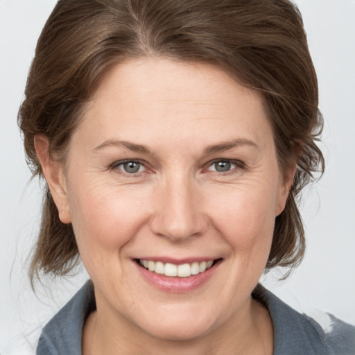 Joyful white adult female with medium  brown hair and grey eyes