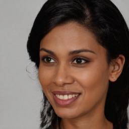 Joyful black young-adult female with long  brown hair and brown eyes