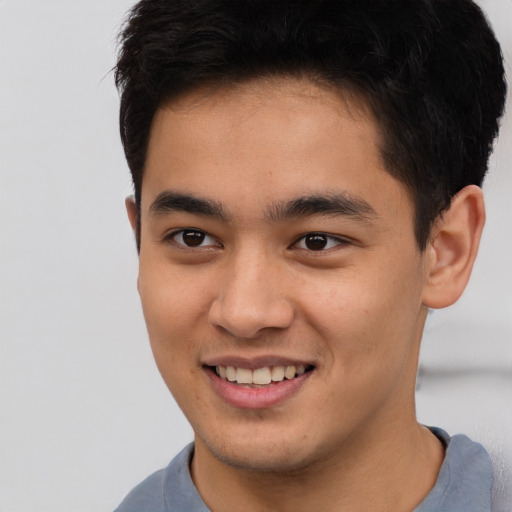 Joyful asian young-adult male with short  brown hair and brown eyes