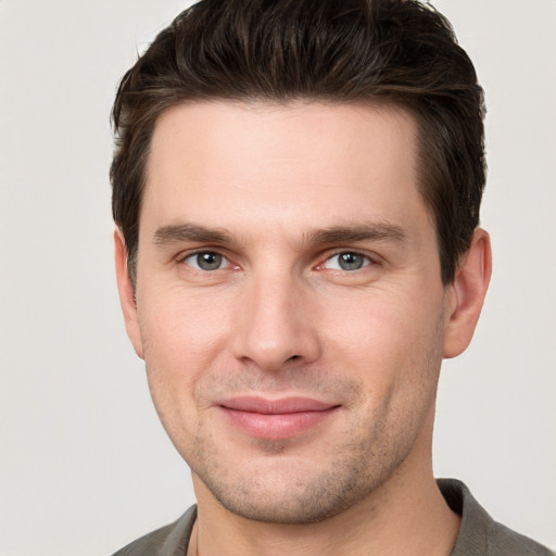 Joyful white young-adult male with short  brown hair and grey eyes