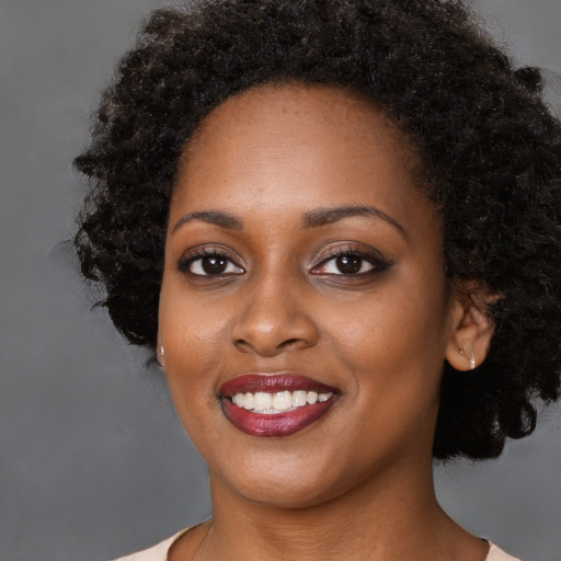 Joyful black young-adult female with medium  black hair and brown eyes