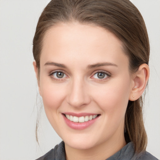 Joyful white young-adult female with medium  brown hair and grey eyes