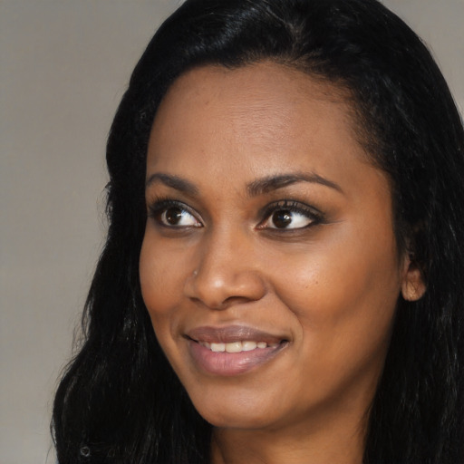 Joyful black young-adult female with long  black hair and brown eyes