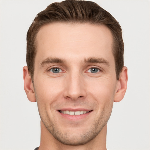 Joyful white young-adult male with short  brown hair and grey eyes