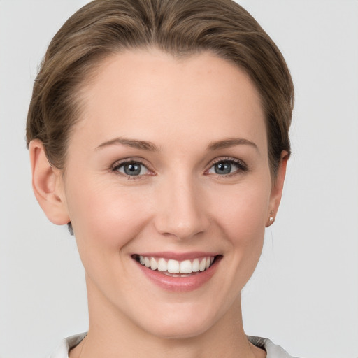 Joyful white young-adult female with short  brown hair and grey eyes