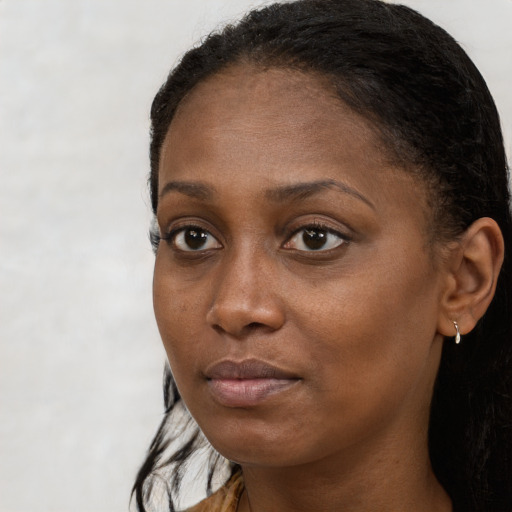 Joyful black young-adult female with long  brown hair and brown eyes
