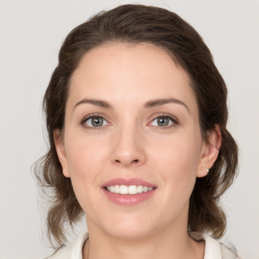 Joyful white young-adult female with medium  brown hair and grey eyes