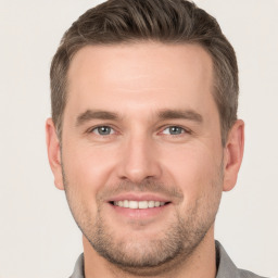 Joyful white young-adult male with short  brown hair and grey eyes