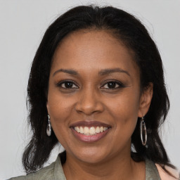 Joyful black young-adult female with long  brown hair and brown eyes