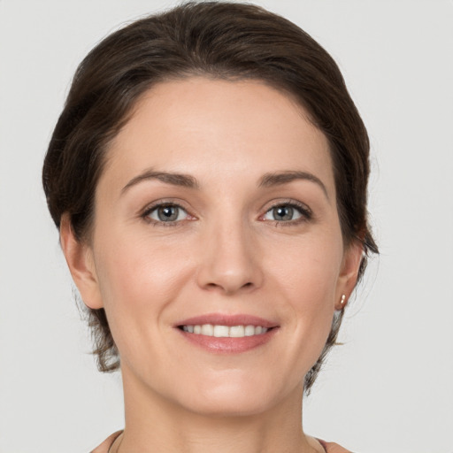 Joyful white young-adult female with medium  brown hair and grey eyes