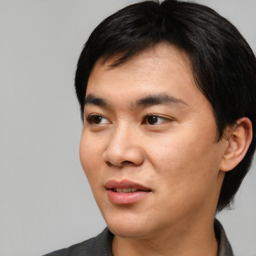 Joyful asian young-adult male with medium  black hair and brown eyes
