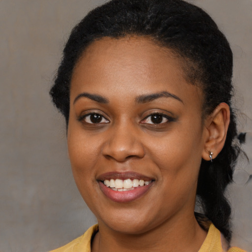 Joyful black young-adult female with long  black hair and brown eyes