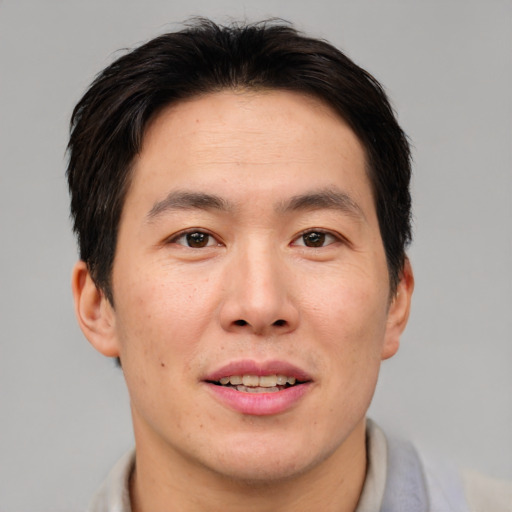 Joyful asian adult male with short  brown hair and brown eyes