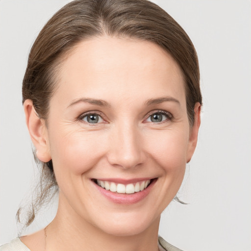 Joyful white young-adult female with medium  brown hair and grey eyes