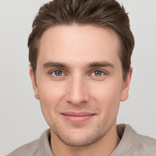 Joyful white young-adult male with short  brown hair and grey eyes