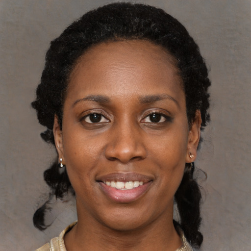 Joyful black young-adult female with long  black hair and brown eyes