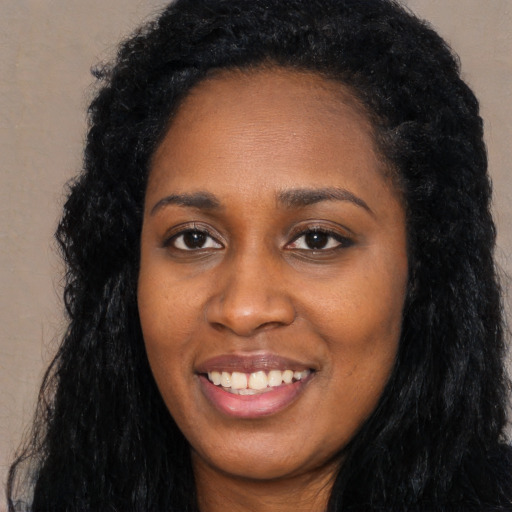 Joyful black young-adult female with long  black hair and brown eyes