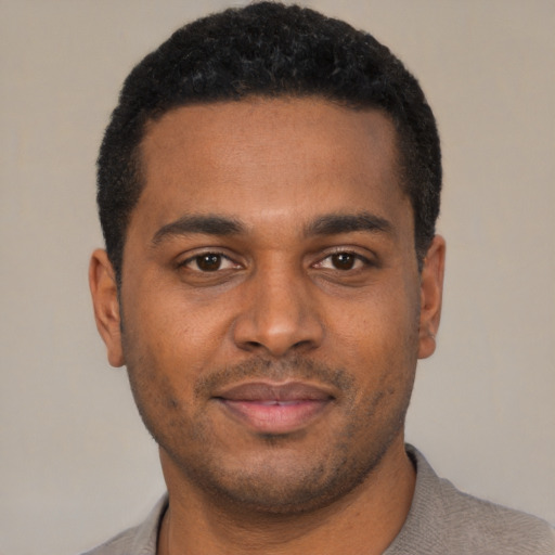 Joyful black young-adult male with short  black hair and brown eyes
