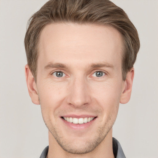 Joyful white young-adult male with short  brown hair and grey eyes