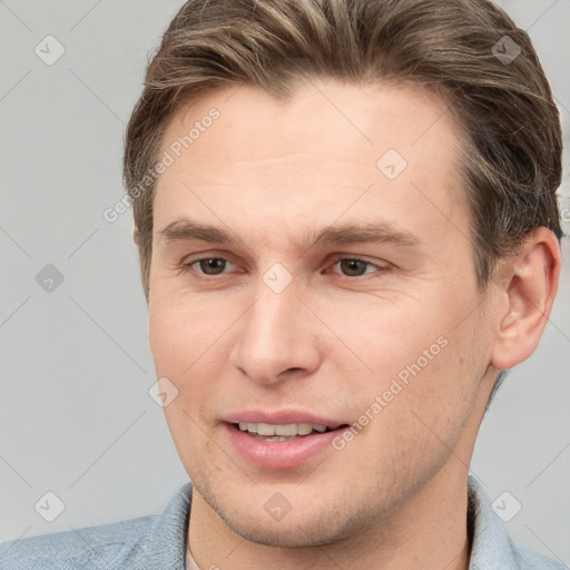 Joyful white young-adult male with short  brown hair and grey eyes