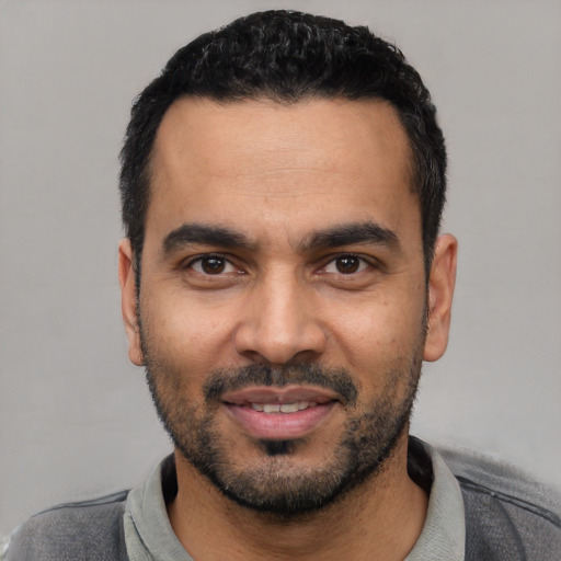 Joyful latino young-adult male with short  black hair and brown eyes