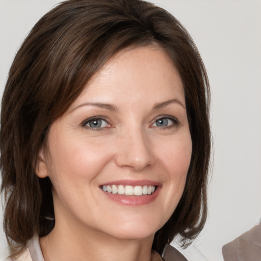 Joyful white young-adult female with medium  brown hair and grey eyes