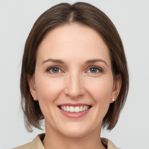 Joyful white young-adult female with medium  brown hair and grey eyes